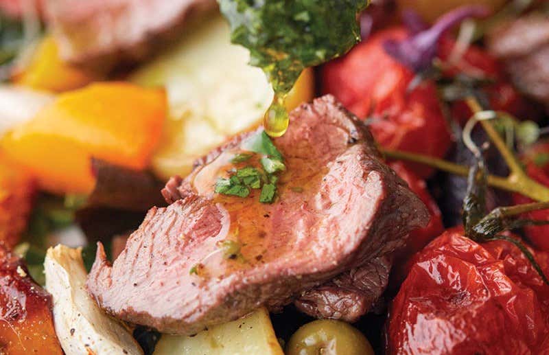 a close up shot of a venison dish with dressing and vegetables