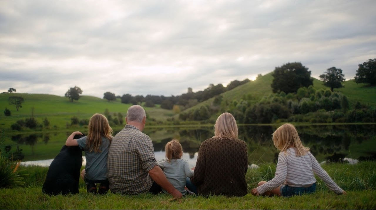 Our farmers and families sitting on grass and looking over farm land and lake