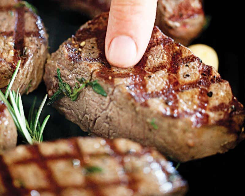 a hand holding a piece of cooked venison
