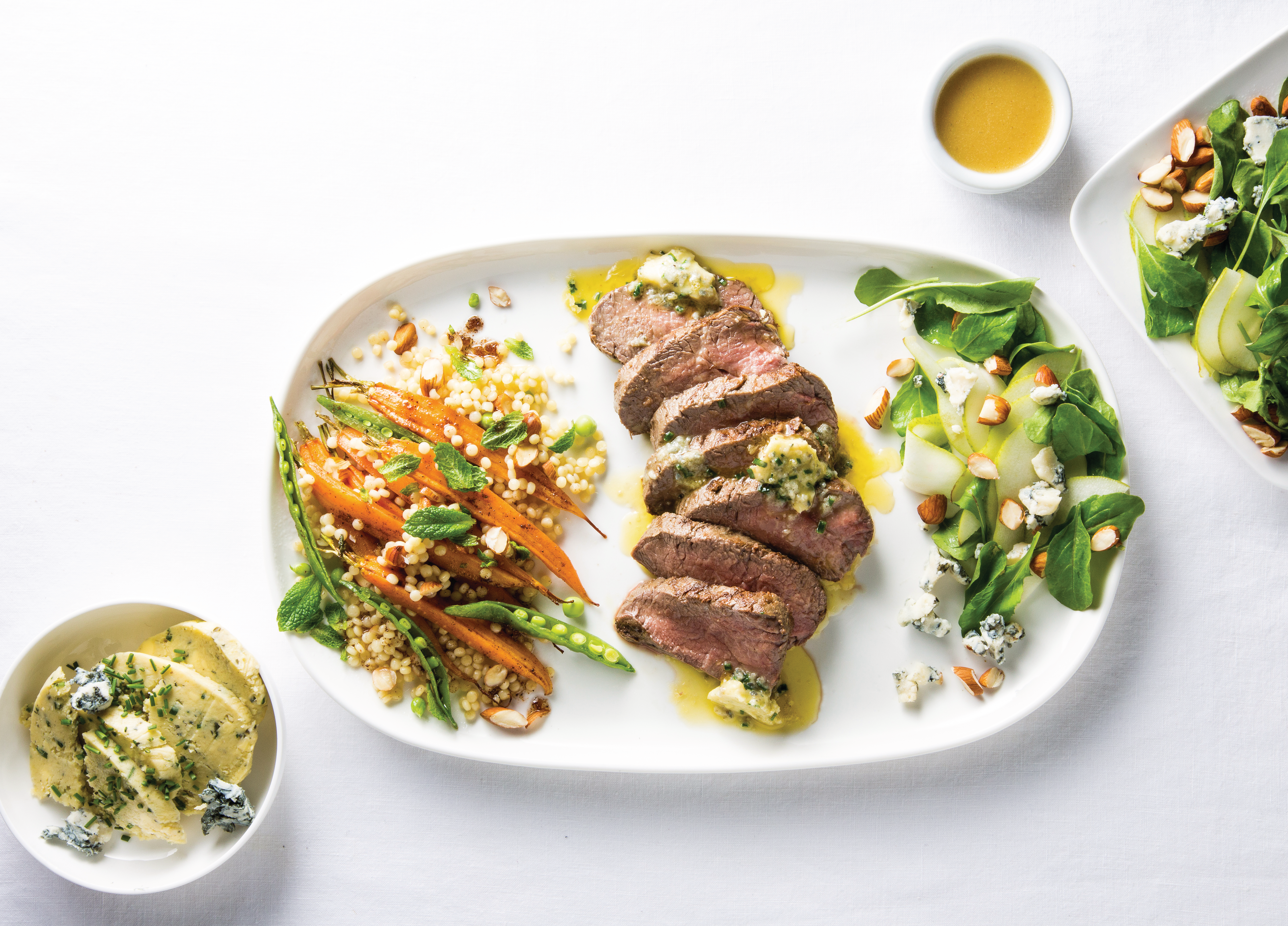 Beef Eye Fillet Steaks with Blue Cheese Butter on a white plate next to salad