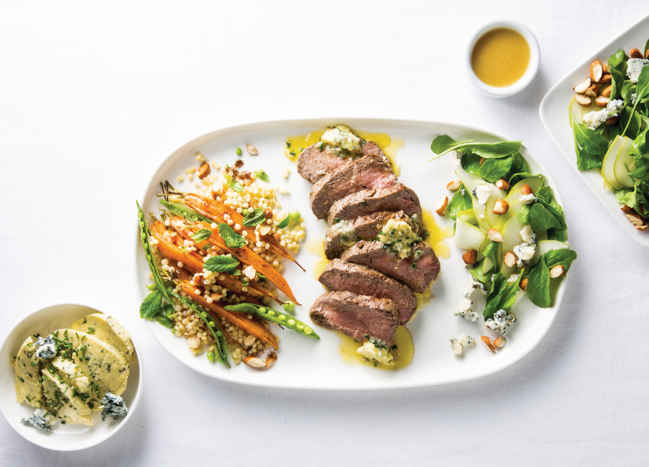 Beef Eye Fillet Steaks with Blue Cheese Butter on a white plate next to salad