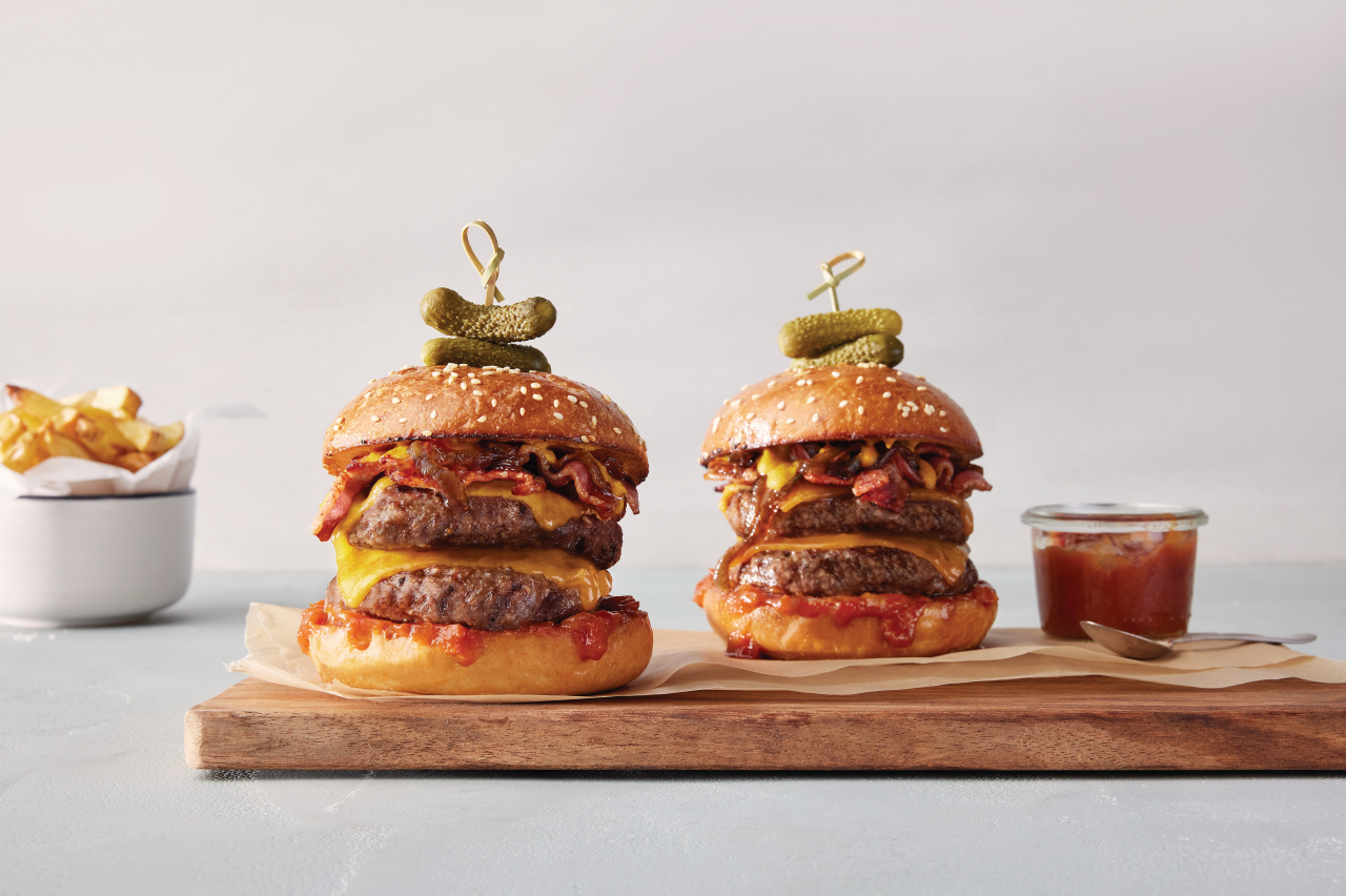 Two Pure Burgers Beef Brisket on wooden board with relish on the side 