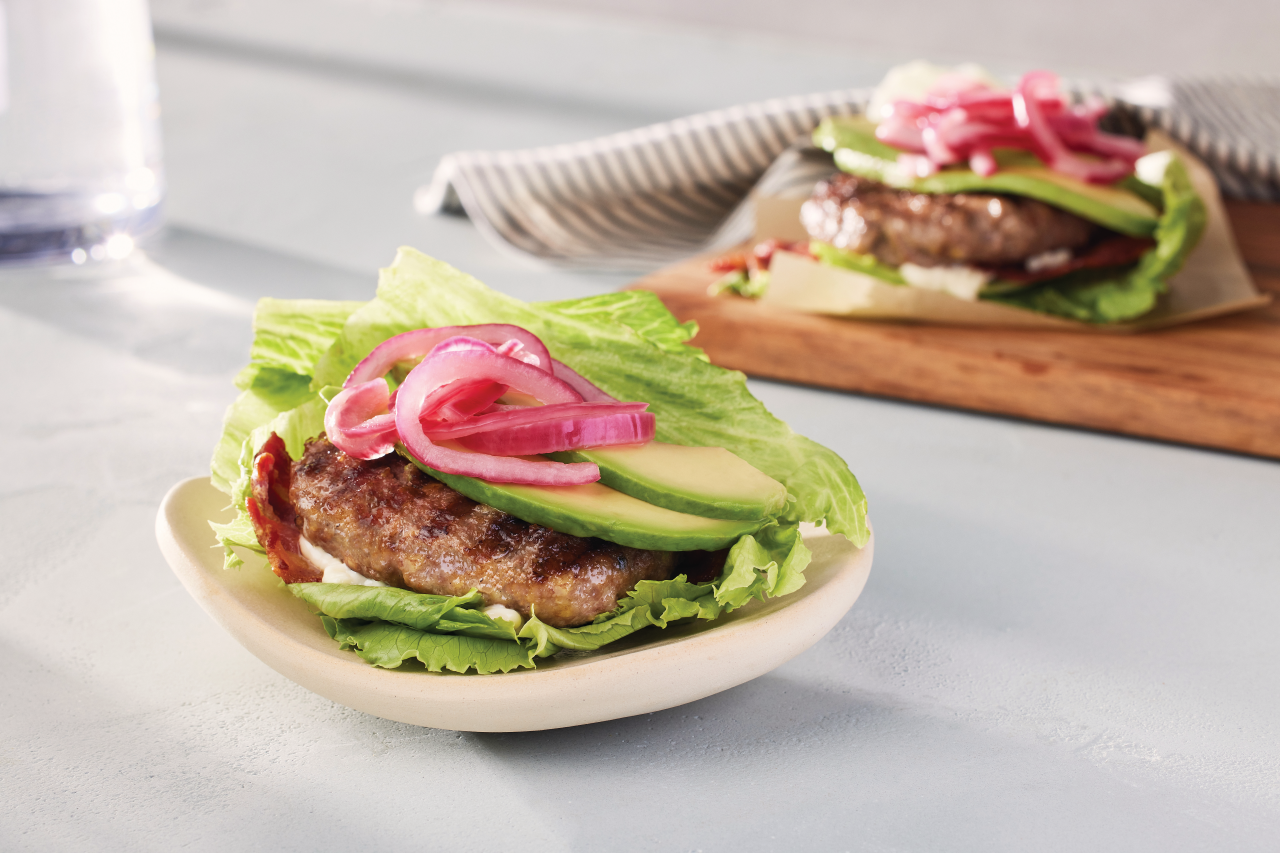 Pure Burger Beef and Venison short rib in a lettuce bun on a small white plate