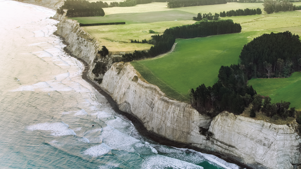 a white cliff face with a farm on top