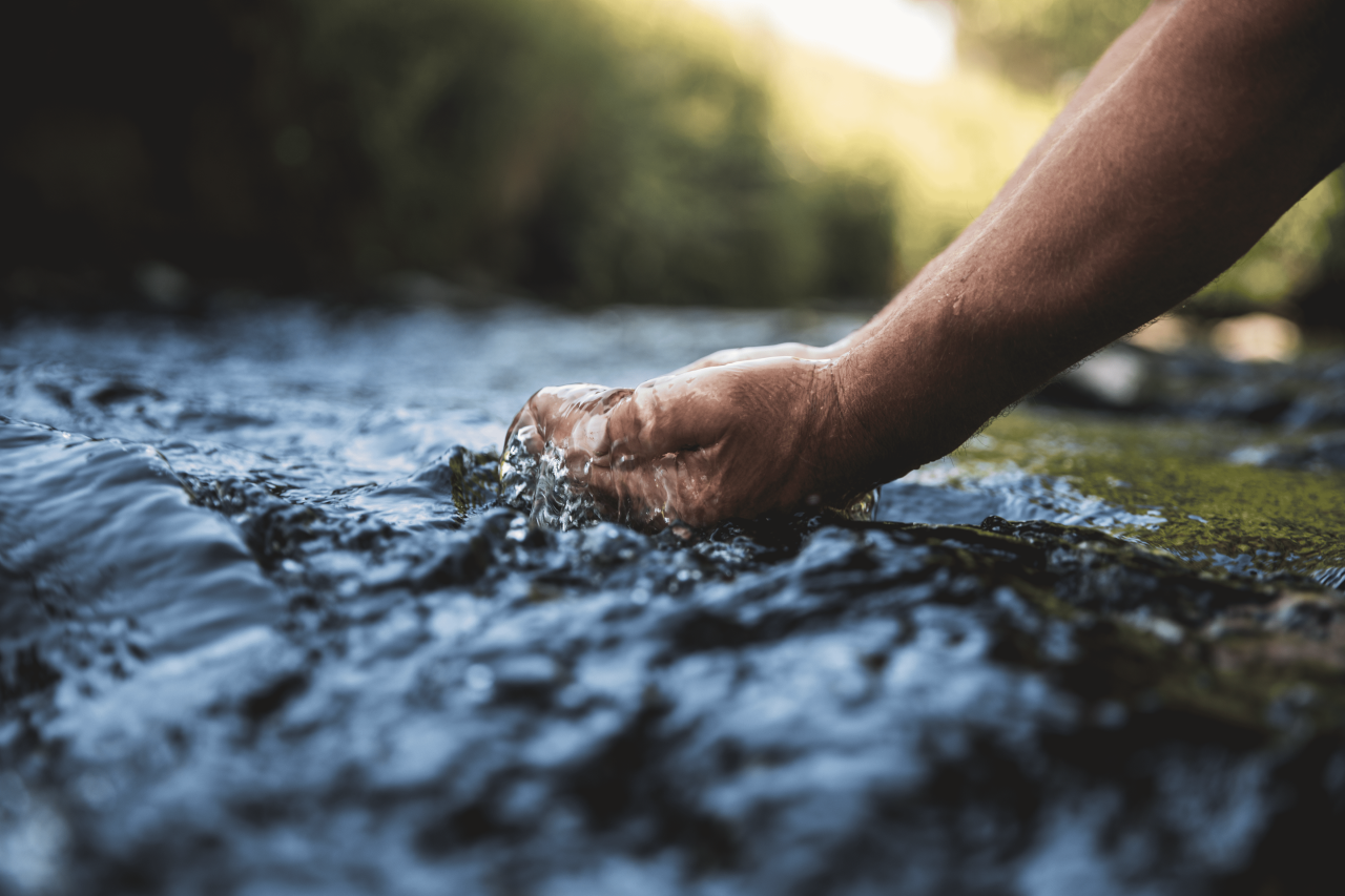 Person submerging hands in spring