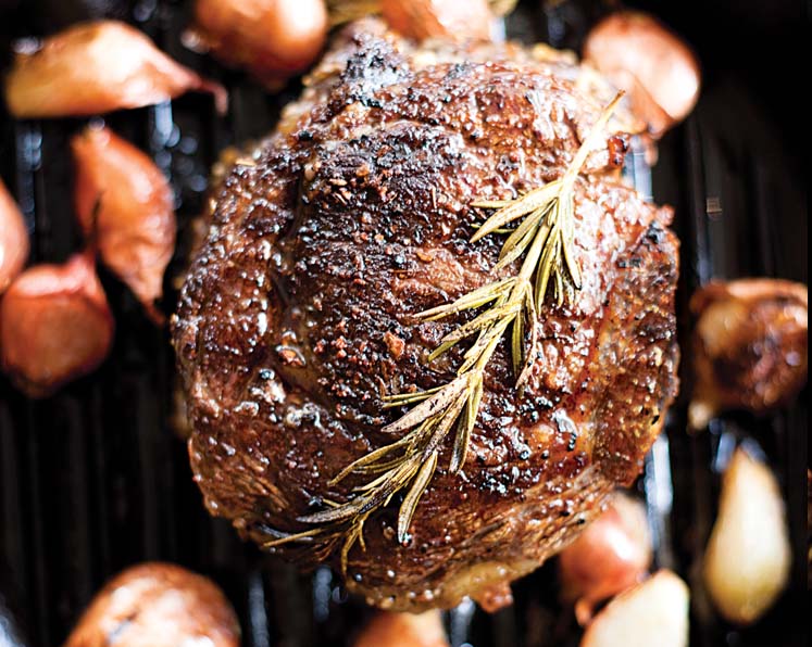 A cooking piece of steak with rosemary on top