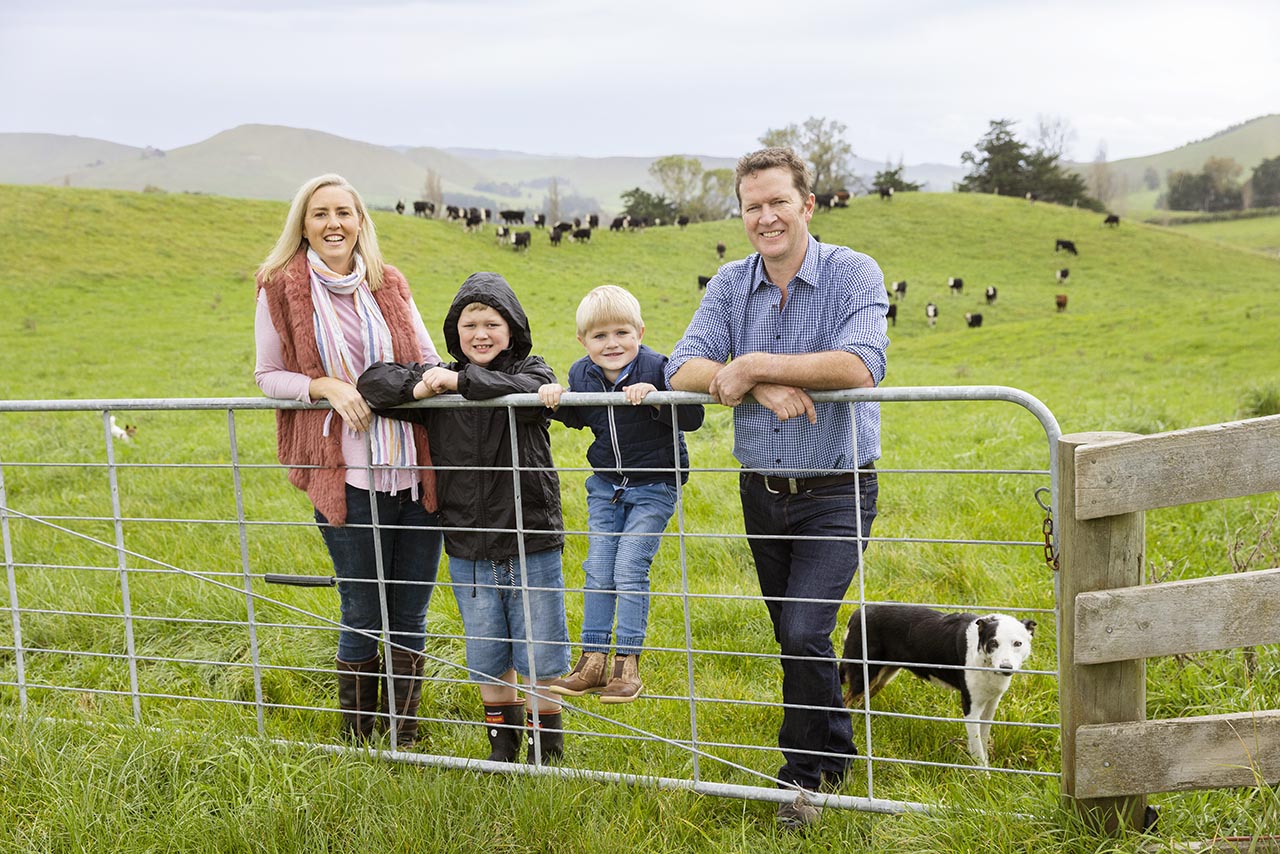 Will and Abbie Foley with their two sons standing being a farm gate