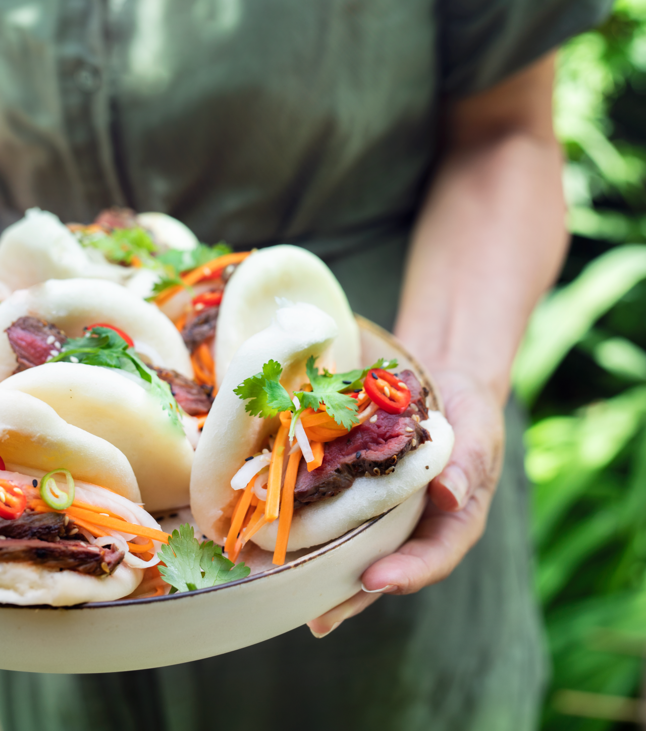 Bao Buns with Venison Steaks and Pickled Daikon on a plate being held