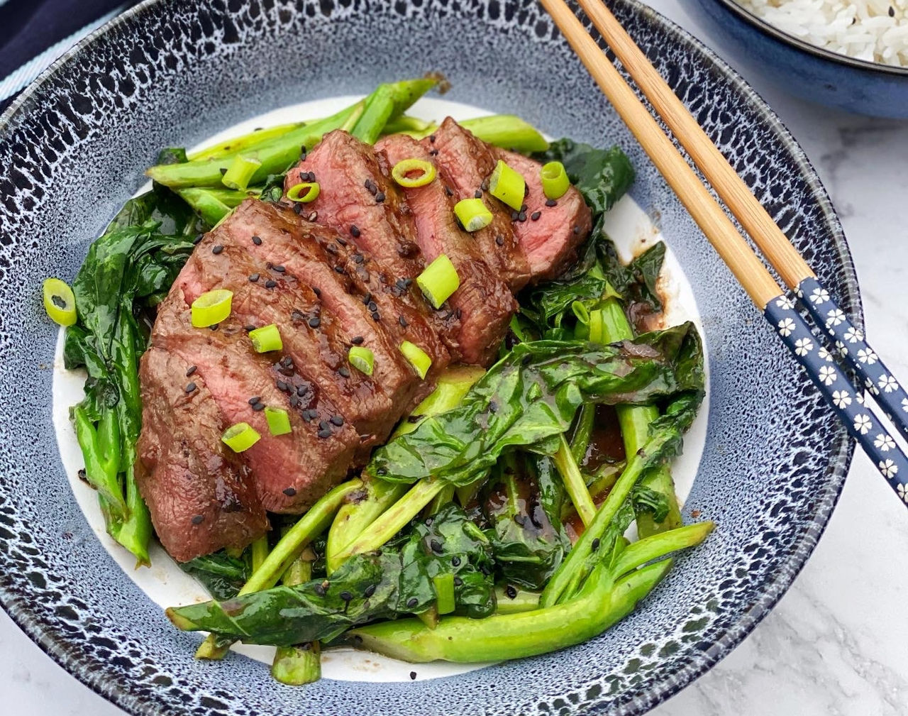 black bean garlic eye fillet beef steaks with gai lan in a blue bowl