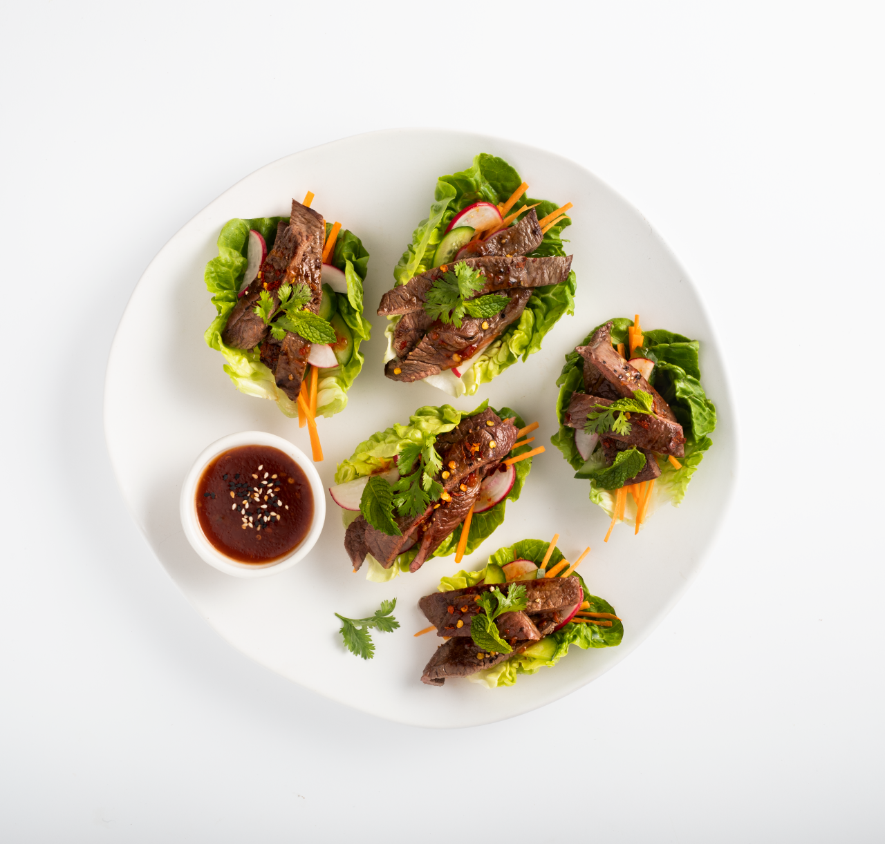 Venison Minute Steaks with Lettuce Cups and Sweet Chilli on a white plate with dipping sauce
