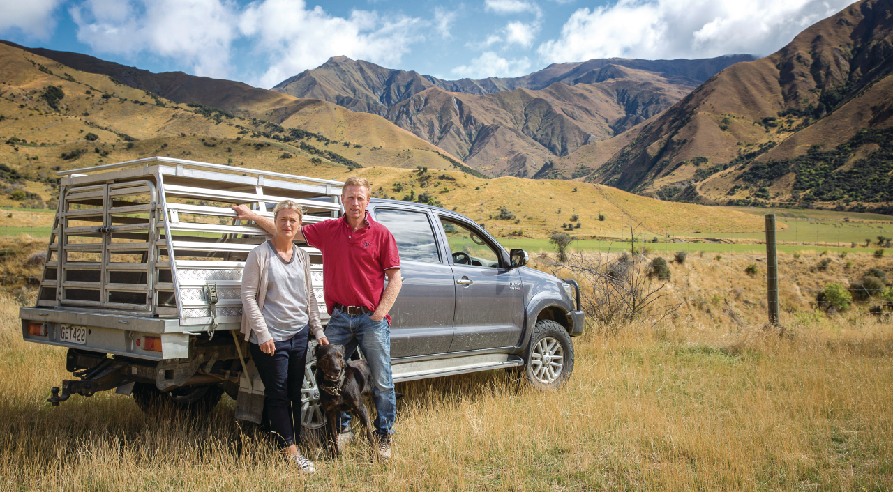 hamish and anna mackay standing next to a truck with their dog