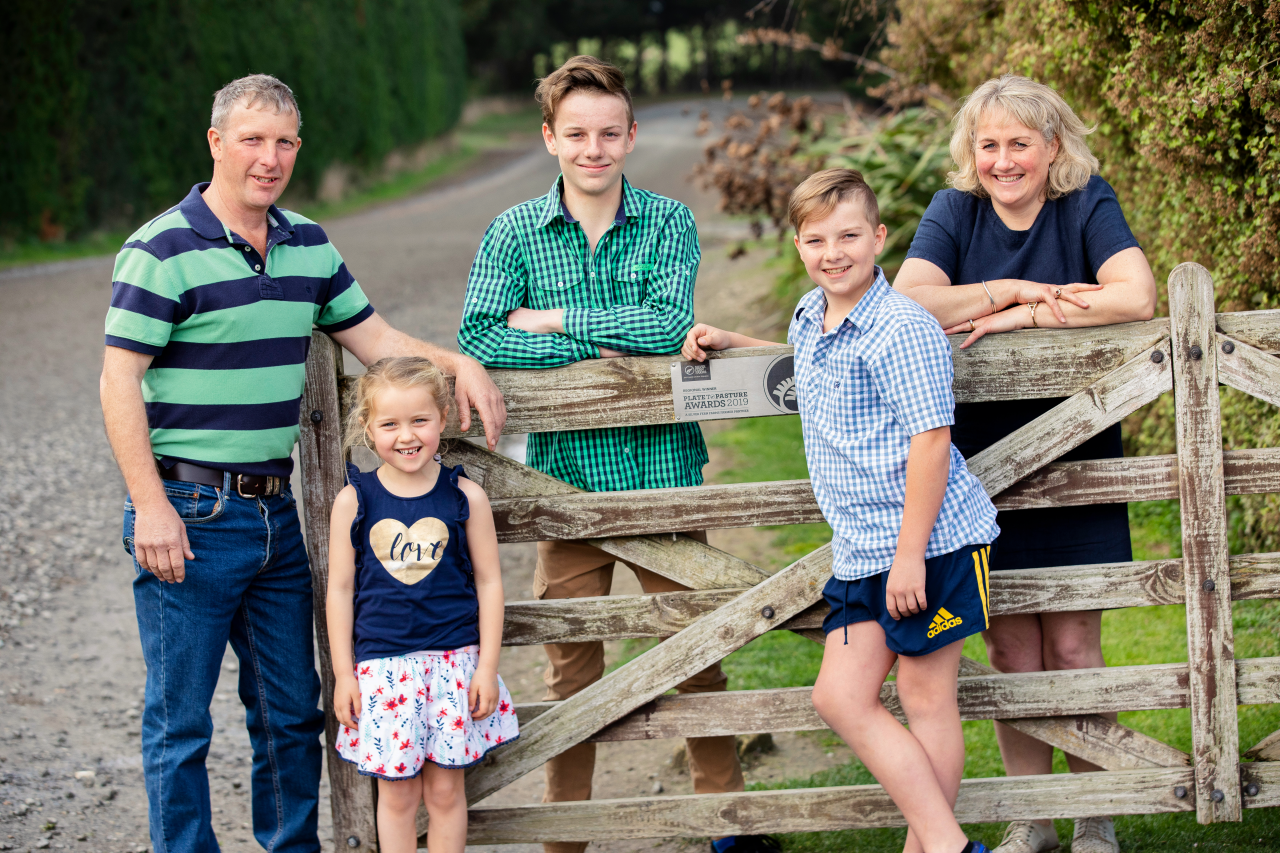 Farmer Story: Maurice and Renee Judson with children leaning against their front gate