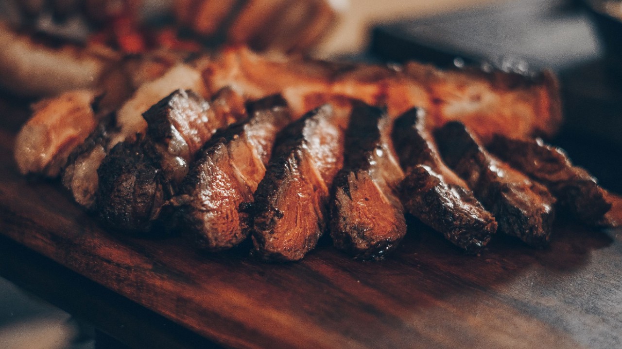 Crispy beef with pink centre sits on a rustic wooden serving tray